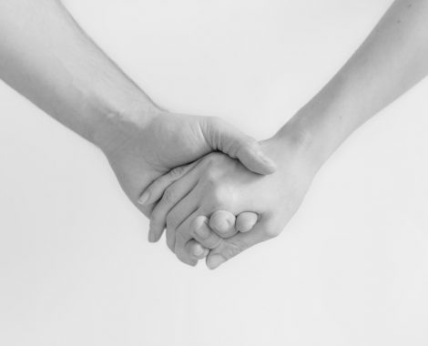 Zwei Menschen halten sich an den Händen.